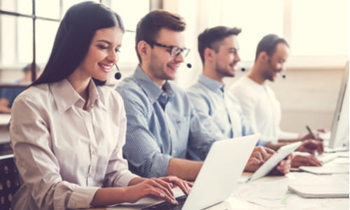 customer service reps with headsets smile and look at their computers